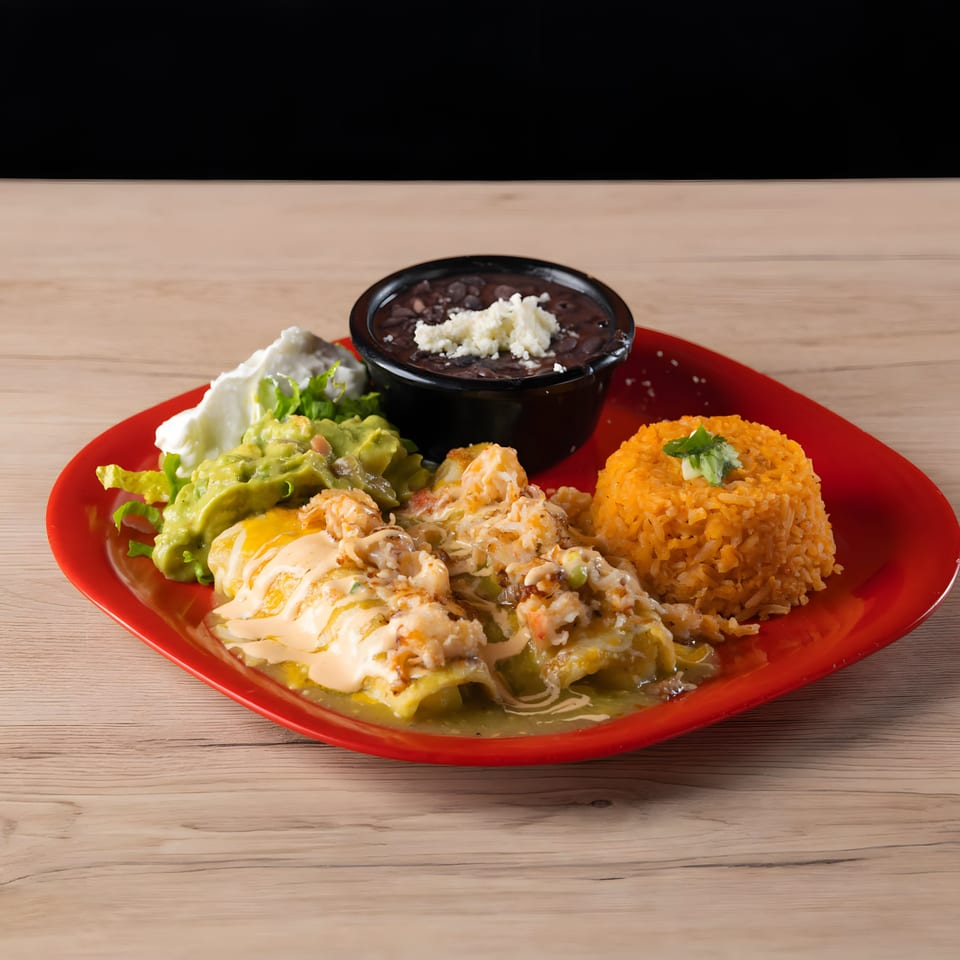 Mexican enchiladas with rice, black beans, guacamole, and sour cream on a red plate.